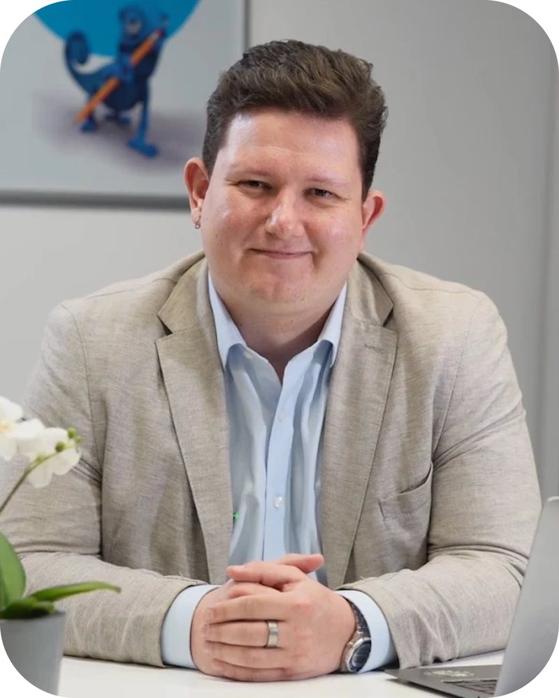 Petr Springinsfeld sedí u stolu v kanceláři a usmívá se do objektivu